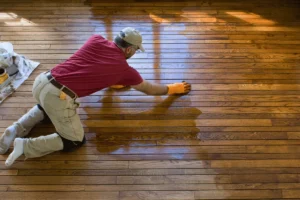 Professional contractor applying stain during a deck and floor refinishing service.